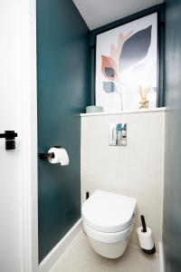a bathroom with a toilet and a blue wall at Luxury new built split-level flat with rooftop gardens access in Manchester