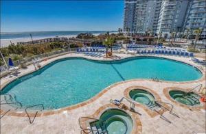 a large swimming pool with chairs and the beach at Sea Watch Resort in Myrtle Beach