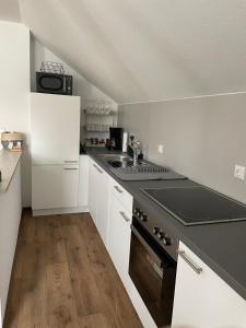 a kitchen with white cabinets and a stove top oven at Ferienwohnung Ela in Bad Kissingen