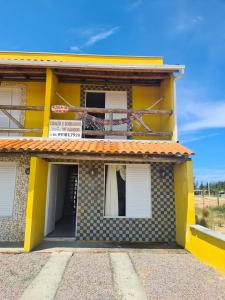 un edificio amarillo con un cartel en el costado en Recanto das Pedras- Casa Pedra Ardósia - Com vista para o mar en Jaguaruna