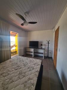 - une chambre avec un lit et un ventilateur de plafond dans l'établissement Recanto das Pedras- Casa Pedra Ardósia - Com vista para o mar, à Jaguaruna