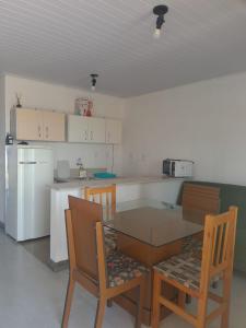 a kitchen with a table and chairs and a refrigerator at Recanto das Pedras- Casa Pedra Ardósia - Com vista para o mar in Jaguaruna