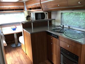 an rv kitchen with a sink and a microwave at Gezellige luxe caravan met zwembad in zuid- Bourgogne in Anglure-sous-Dun