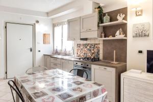 a kitchen with white cabinets and a table with chairs at N213 - Numana, nuovo bilocale in centro in Numana