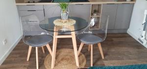 a glass table with two chairs and a vase on it at Charmant logement neuf in Hourtin