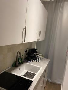 uma cozinha com um lavatório e armários brancos em Nice104 em Turim
