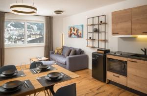 a kitchen and living room with a table and a couch at Auhof - Apartments Bad Gastein in Bad Gastein