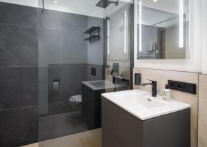 a bathroom with a sink and a toilet and a mirror at Auhof - Apartments Bad Gastein in Bad Gastein +31 photos