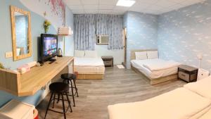 a room with two beds and a desk with a television at Fengjia Gift Box Homestay in Taichung