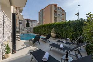 a patio with lounge chairs and a swimming pool at Holiday apartments Stobrec in Split