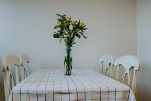 un vase de fleurs sur une table avec des chaises dans l'établissement Uist Travel Accommodation, à Daliburgh