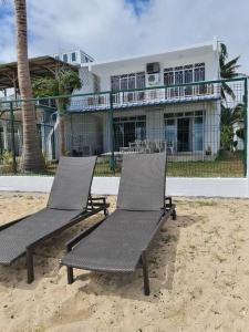 deux chaises assises dans le sable devant une maison dans l'établissement Vacation Beach House South of Mauritius - Riambel, à Riambel