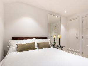 a bedroom with a white bed with a large mirror at 5 Clough Cottages in Clitheroe