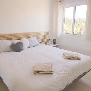 Un dormitorio con una cama blanca con toallas. en Beach Front Sea View Punta Prima en Punta Prima