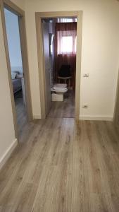 an empty room with wooden floors and a room with a toilet at Casa Angelina in Rome