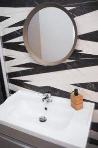W łazience znajduje się biała umywalka i lustro. w obiekcie Melody Apartment w Krakowie