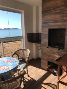 sala de estar con TV, mesa y sillas en Melhor vista para o mar, en Penha