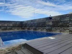 una piscina con terraza de madera junto a una pared de ladrillo en Confortable y Moderno Studio en Santa Cruz de la Sierra