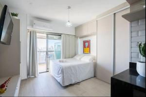 een witte slaapkamer met een bed en een groot raam bij Studio vista para cidade in Sao Paulo