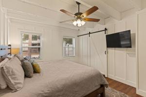 ein Schlafzimmer mit einem Bett mit Deckenventilator und einem Flachbildfernseher in der Unterkunft Sea Side Cottage - 4217 Second Street in East End