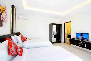 Habitación blanca con 2 camas y TV en Degung de brata Family villas, en Legian