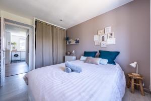 a bedroom with a large white bed with blue pillows at Confort Golf Disney in Bailly-Romainvilliers