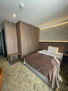 Hotel Terme 36.6 في Priboj: غرفة نوم بسرير كبير وجدران خشبية