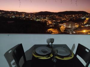 a dining table with a view of a city at night at Apartamento Por do Sol - Cobertura in São Roque