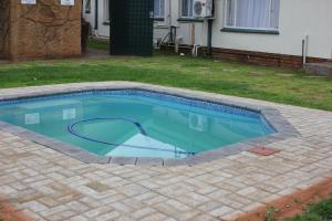 a small swimming pool in a yard with a house at El Palmar Guesthouse in Groblersdal