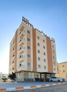 un edificio de hotel con un coche aparcado delante de él en Grand Orchid Hotel Apartment, en Duqm