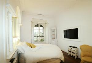 ein weißes Schlafzimmer mit einem Bett und einem TV in der Unterkunft Secret Garden Villa Borghese in Rom