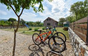 duas bicicletas estacionadas ao lado de uma cerca com um parque infantil em Gorgeous Home In Trilj With House A Mountain View em Trilj