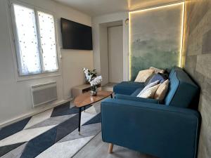 sala de estar con 2 sillas azules y mesa en suite spa jacuzzi tout confort, en Beaumont-sur-Oise