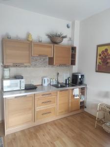 Kuchnia z drewnianymi szafkami, zlewem i kuchenką mikrofalową w obiekcie Apartamenty Przytulny - Pod Aniołem w Kazimierzu Dolnym