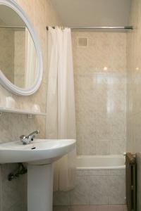 a bathroom with a sink and a shower with a mirror at Pensión Casa Cesáreo in Pola de Somiedo