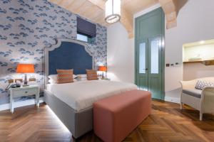 a bedroom with a large bed and a chair at Palazzo Bifora Mdina in Mdina