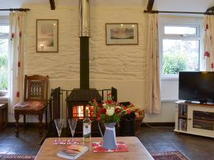 a living room with a fireplace and a table with flowers at Trenay Barns Cottage in Warleggan