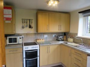 a kitchen with wooden cabinets and a white stove top oven at Trenay Barns Cottage in Warleggan