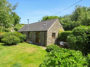 a stone cottage in a garden with a yard at Trenay Barns Cottage in Warleggan