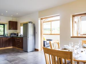 a kitchen and dining room with a table and a refrigerator at Heyope Cottage in Llangunllo