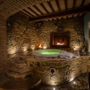a stone bathroom with a tub with a fireplace at PALAZZO DEL CAPITANO Wellness & Relais - Luxury Borgo Capitano Collection in San Quirico dʼOrcia
