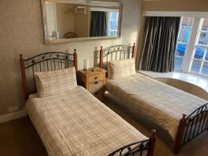 a bedroom with two beds and a tub and a mirror at Mason's Arms in Norham