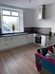 a kitchen with white cabinets and a couch at ARDUTHIE STREET in Stonehaven +29 photos