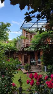 una casa con terraza y rosas en el patio en La cabane du bon chemin ,spa en Laval