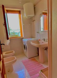 een badkamer met een wastafel, een toilet en een wasmachine bij Alloggio vista mare in Peschici