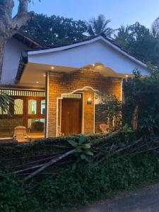 een klein bakstenen huis met een veranda ervoor bij Villa Green Garden in Hikkaduwa