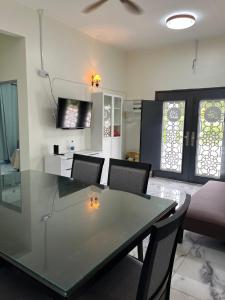 uma sala de jantar com uma mesa de vidro e cadeiras em Rumah Tamu Zeha Muar Johor em Muar