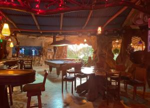 un restaurante con mesas, sillas y un árbol en La Perla Negra Eco Pirate Resort, en Puntarenas