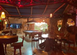 un restaurante con mesas, sillas y un árbol en La Perla Negra Eco Pirate Resort en Puntarenas