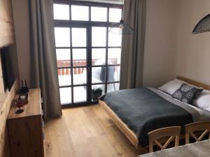 a bedroom with a bed and a large window at Strunzova Pila - apartmány s wellness 2,06 a 3,03 in Kvilda